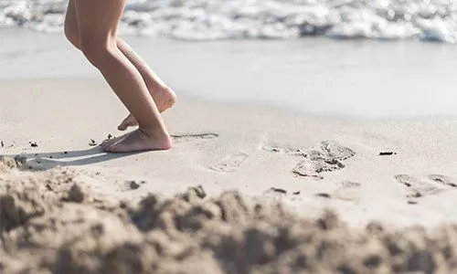 Jambes d'enfant qui marche dans le sable